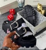 A pair of black sandals with silver buckles, showcased in a luxurious setting with Alexander McQueen branding, exuding Modern Luxury and Urban Edge.