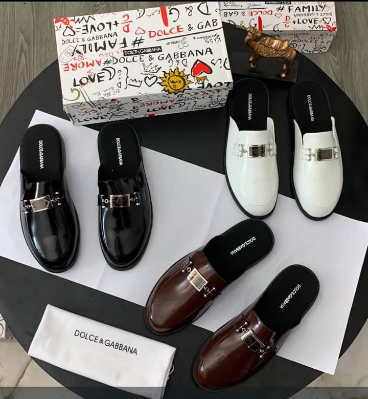 root A stylish display of Dolce & Gabbana half shoes in black, brown, and white, accompanied by the brand's signature box and cloth bag.