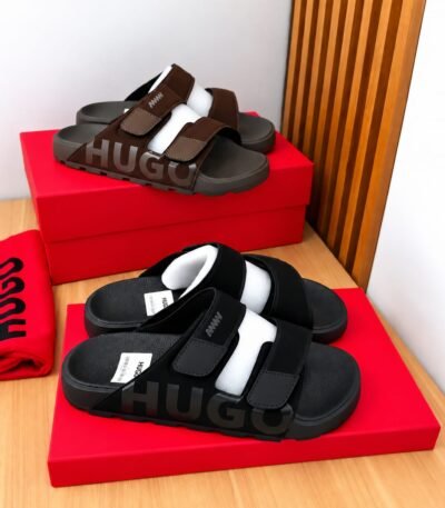 A pair of black and brown HUGO slides on red shoe boxes, showcasing Modern Luxury, Urban Edge, and Timeless Quality.