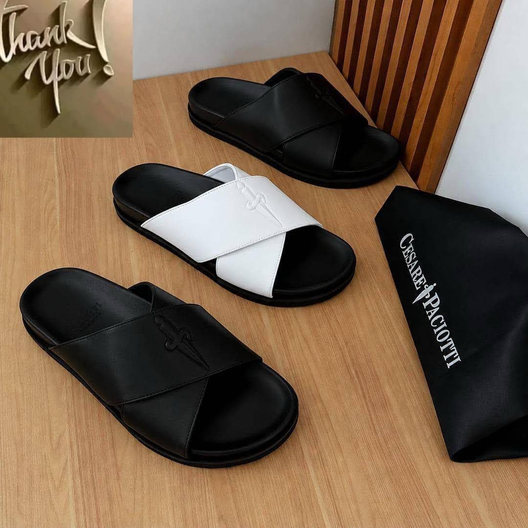 root A stylish display of luxurious slides in black and white, accompanied by a branded dust bag, showcasing modern design and timeless quality.