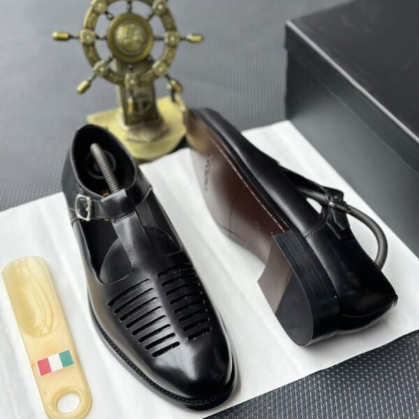 A pair of luxurious black leather monk strap shoes on a white cloth, accompanied by a shoe tree and a decorative ship's wheel, exuding modern luxury and urban edge.