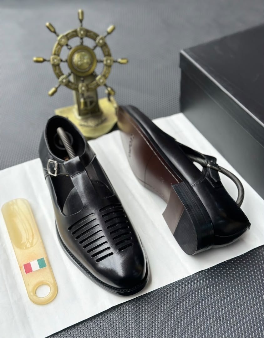 root A pair of luxurious black leather monk strap shoes on a white cloth, accompanied by a shoe tree and a decorative ship's wheel, exuding modern luxury and urban edge.