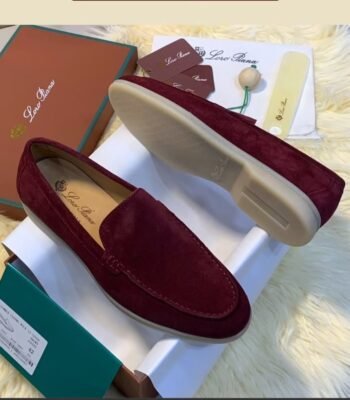 A pair of luxurious maroon loafers displayed on a white box with their matching box and accessories, exuding sophistication and elegance.