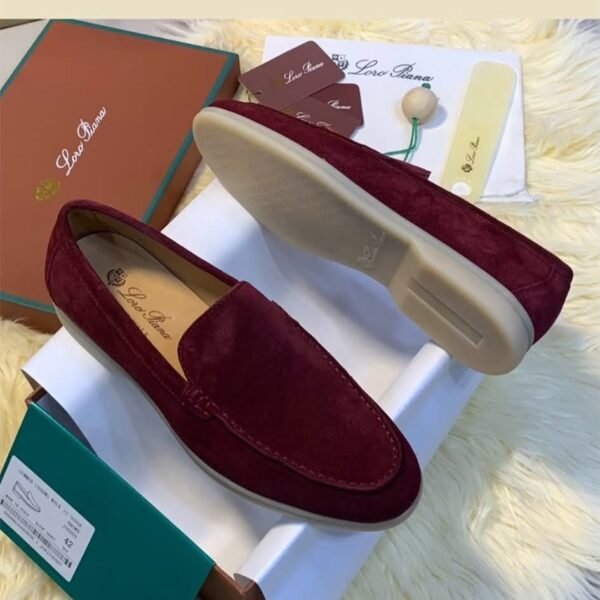 A pair of luxurious maroon loafers displayed on a white box with their matching box and accessories, exuding sophistication and elegance.
