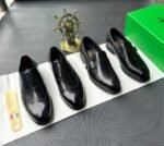 A pair of black leather oxfords with brogue detailing, accompanied by a shoe tree and presented on a crisp white background, evoking a sense of luxury and refinement.