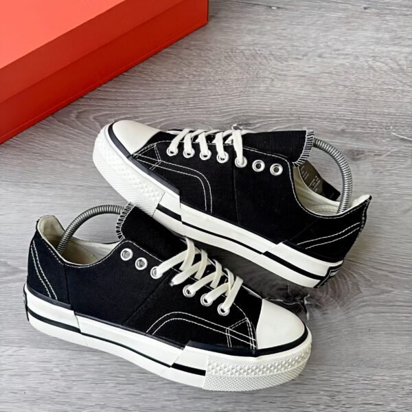 A pair of black sneakers with white laces and soles, showcasing a sleek and modern design.
