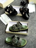 A pair of black sandals with silver buckles, showcased in a luxurious setting with Alexander McQueen branding, exuding Modern Luxury and Urban Edge.