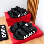 A pair of black HUGO slides on a red shoe box, exuding Modern Luxury and Urban Edge.