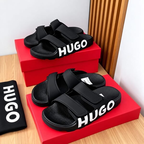 A pair of black HUGO slides on a red shoe box, exuding Modern Luxury and Urban Edge.