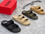 A pair of black and brown HUGO slides on red shoe boxes, showcasing Modern Luxury, Urban Edge, and Timeless Quality.