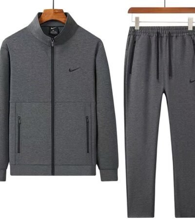 A stylish grey tracksuit consisting of a zip-up jacket and matching joggers, both featuring the Nike logo, displayed on hangers against a white background.