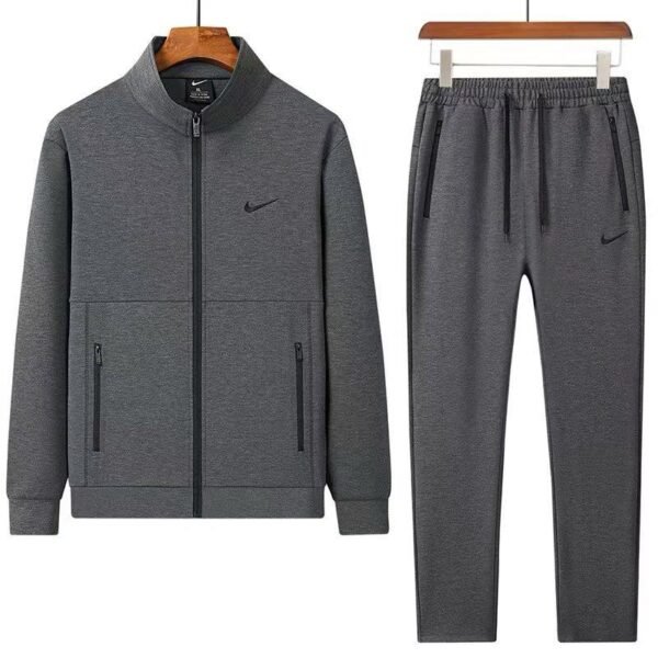 A stylish grey tracksuit consisting of a zip-up jacket and matching joggers, both featuring the Nike logo, displayed on hangers against a white background.