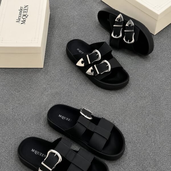 A pair of black slides with silver buckles and two white shoe boxes with 'Alexander McQueen' printed on them.