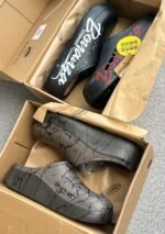 A pair of black clogs with white Bonanza Storm Rider branding and a pair of grey clogs with a cracked pattern, showcasing modern luxury footwear.