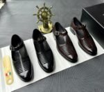 A pair of luxurious black leather monk strap shoes on a white cloth, accompanied by a shoe tree and a decorative ship's wheel, exuding modern luxury and urban edge.