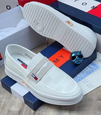 A pair of white Tommy loafers with a blue and red box and a pair of sunglasses
