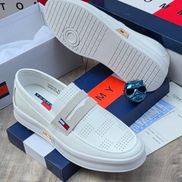 A pair of white Tommy loafers with a blue and red box and a pair of sunglasses