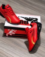A pair of vibrant red Puma sneakers with gold and black accents, exuding Modern Luxury and Urban Edge, placed elegantly on a wooden floor next to their box.